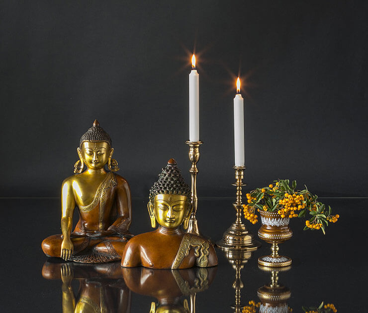 Buddha statues with candleholders and a small vase
