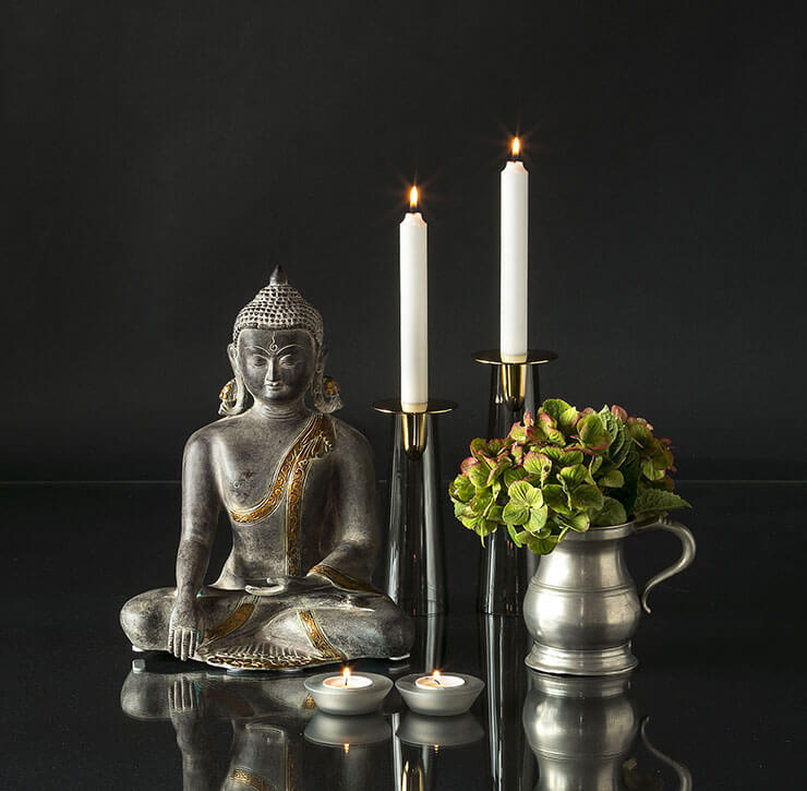 Buddha statue with candleholders and jar with flowers
