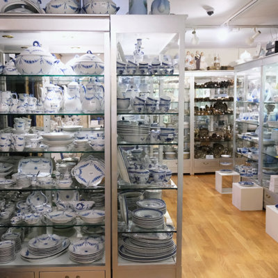 Glass display cabinet at the Danish Porcelain House in Odense, Denmark, featuring blue and white porcelain from Royal Copenhagen and Bing & Groendahl – including Blue Fluted, Tranquebar, and Empire dinnerware.