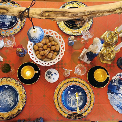Christmas table set with Bing & Groendahl Christmas plates, Bjørn Wiinblad Christmas plates, and Komponist service cups, combined with other dinnerware pieces. The table is arranged in shades of blue, gold, and red.
