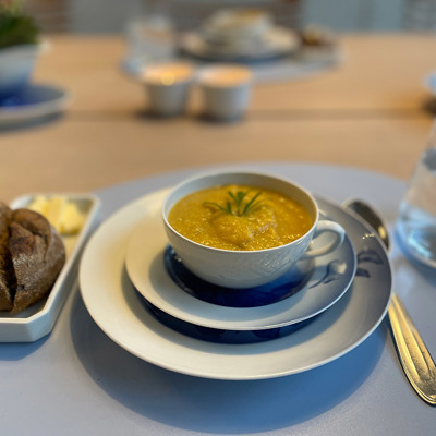 Old porcelain teacup used for serving soup as a starter, arranged with bread and butter. A creative and personal table setting.
