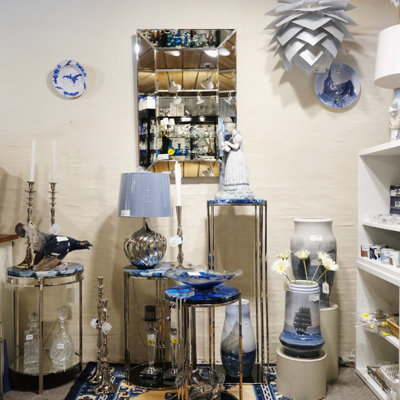 Display at the Danish Porcelain House with modern glass vases, classic porcelain figurines, lamps, and candleholders – a stylish mix of new and old in shades of blue and silver.