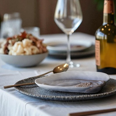 Bing & Groendahl porcelain bowl with a water lily motif used for serving fish. Table setting with a white tablecloth, wine glasses, and a wine bottle on the table.