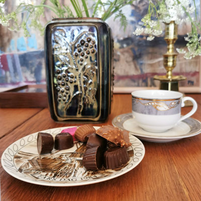 Egemose Father’s Day plate used as a cake plate with chocolate, combined with a Magnolia coffee cup and a vase with decoration in the background.