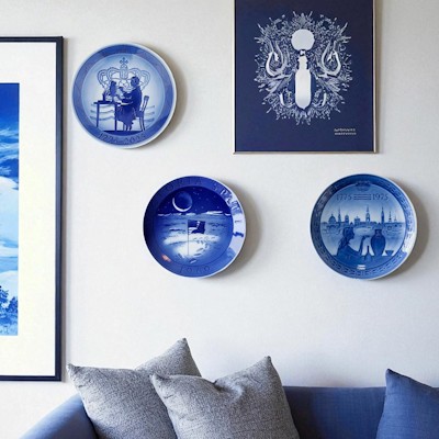Royal Copenhagen commemorative plates and anniversary plates hung on a picture wall as part of modern home decor.