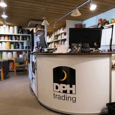 The counter at the Danish Porcelain House with a computer and customer service area in front of large shelves filled with lampshades in many colors and sizes.