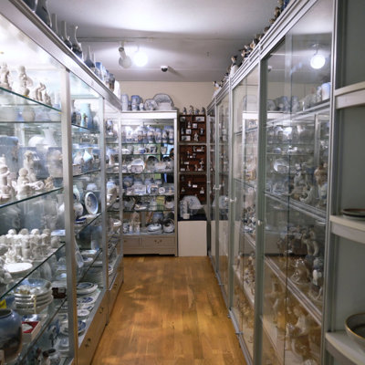 Glass display cabinet at the Danish Porcelain House in Odense, Denmark, featuring vases, bowls, and porcelain figurines from Royal Copenhagen, Bing & Groendahl, Lyngby Porcelain, and Dahl Jensen.