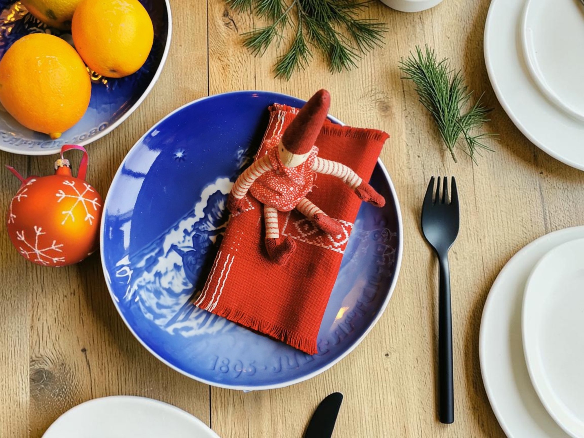 Bing & Groendahl Christmas anniversary plate set with red napkin and elf on Christmas table with pine and Christmas decorations