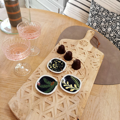 Rörstrand flower mini plates used as small dishes for serving chocolate, arranged on a wooden board with rosé in glasses.