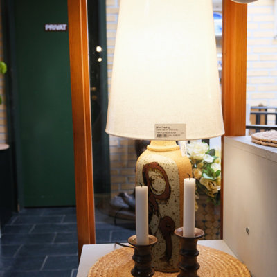 Ceramic table lamp with a light fabric shade and two ceramic candleholders – displayed on one of the shelves at the Danish Porcelain House store in Odense, Denmark.