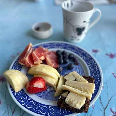 Rörstrand Mother’s Day plate used as a breakfast plate with fruit, rye bread with cheese, and coffee. An example of how blue plates can be used in everyday settings.