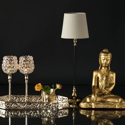 Buddha next to small lamp and mirror tray with candle holders