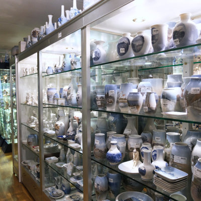 Large glass display cabinets at the Danish Porcelain House in Odense, Denmark, filled with vases and porcelain from Royal Copenhagen, Bing & Groendahl, and Lyngby Porcelain – many with hand-painted designs.